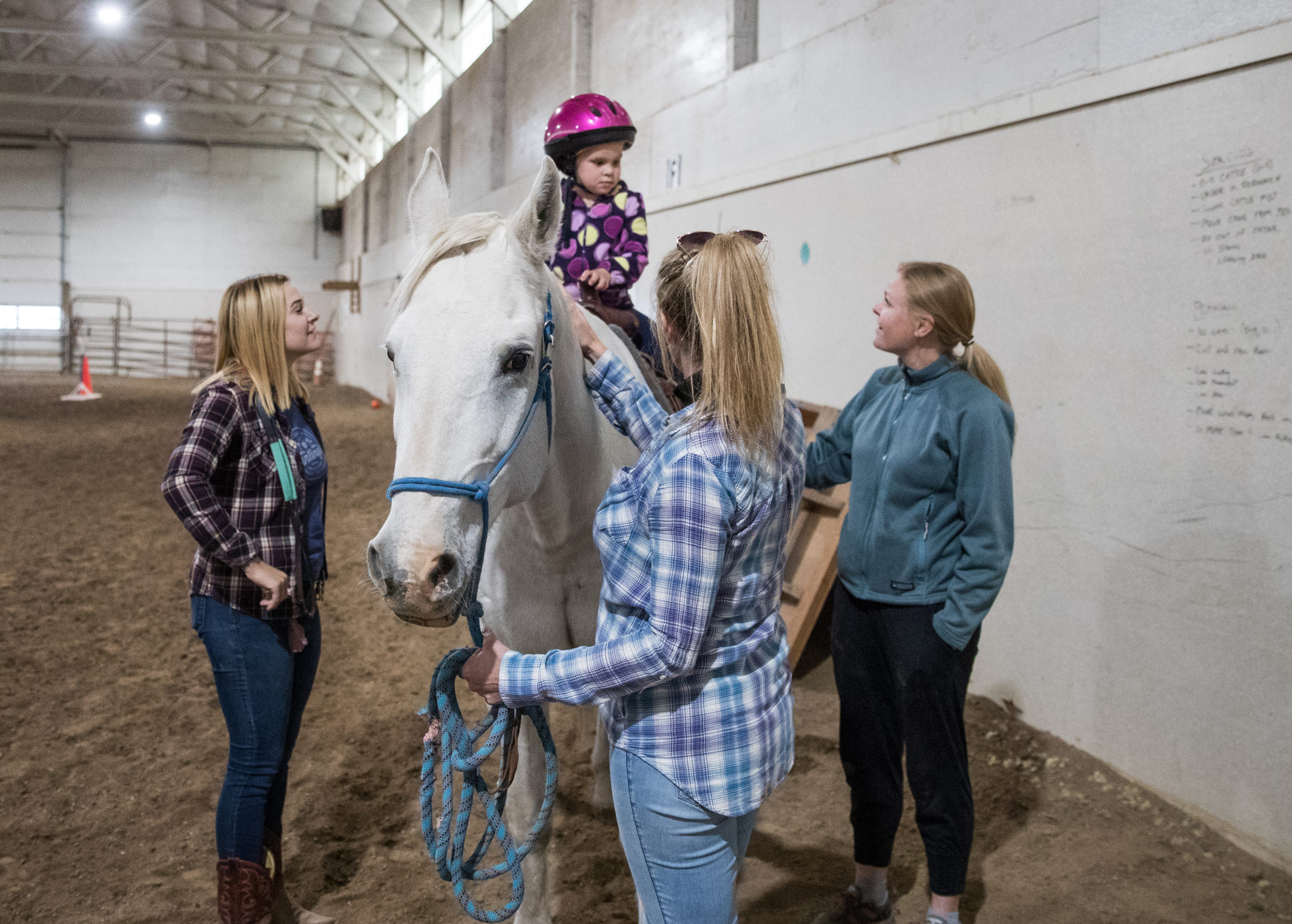 Erica Sandiland (right) helps her daughter, Hazel Guerette, as she gets on her lesson horse of the day. Guerette, 4, is participating in an “equine-assisted activity” session at Trotting Horse Therapeutic Riding, where she works to improve her core strength and motor skills.
