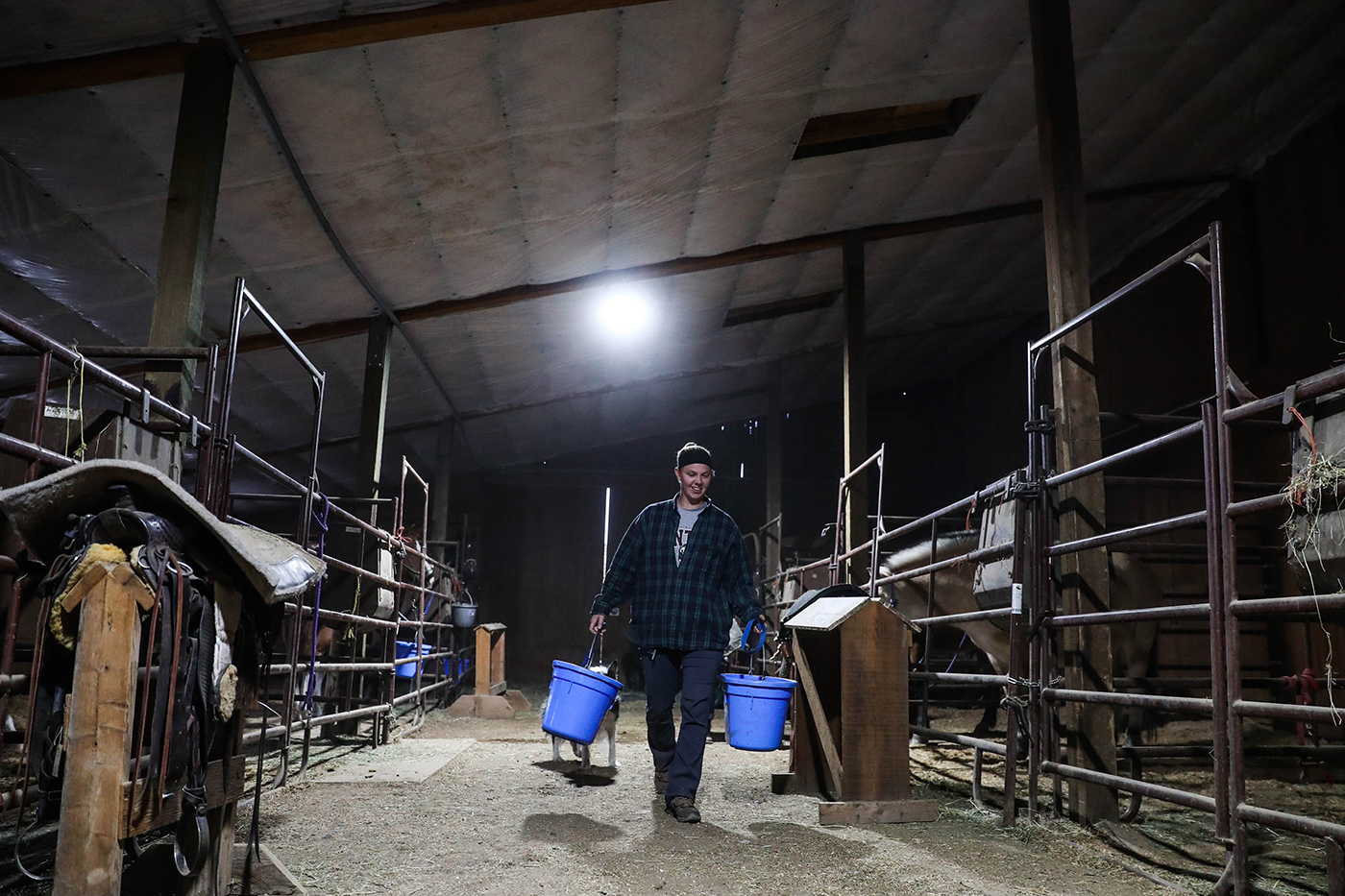 Volunteer Kelly Lorton hauls grain buckets to lesson horses that have finished for the day. Lorton has been a volunteer for a year and a half.