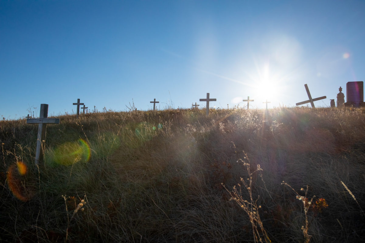 The cemetery on the grounds of the St. Peter’s Mission houses numerous white crosses symbolizing unmarked graves. In recent discoveries of unmarked graves at other boarding schools in the U.S. and Canada, bodies of boarding school children were found.